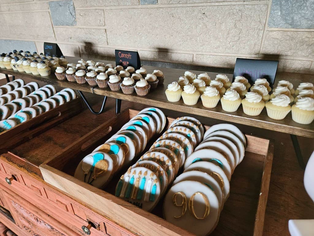 Hand-decorated cookies and cupcakes arranged on a dessert table